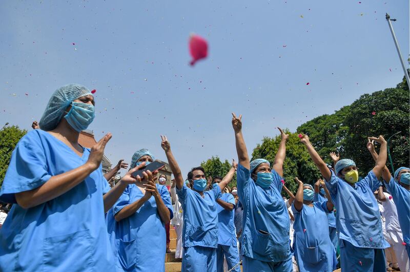 Medical staff cheer as an Indian Air Force helicopter drops flower petals over the Victoria Hospital in Bangalore. AFP