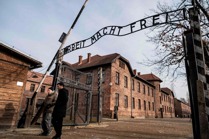 Holocaust survivor and former prisoner of the Nazi death camp Auschwitz-Birkenau, Johnny (Ephroim) Jablon (L), crosses the gate with the inscription reading "Work sets you free" (Arbeit macht frei) in Oswiecim on January 26, 2020, a day before the 75th anniversary of its liberation. Wojtek Radwanski / AFP