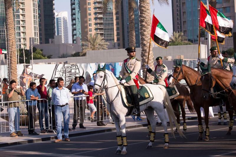 Officers on horseback hold the UAE flag high as they march