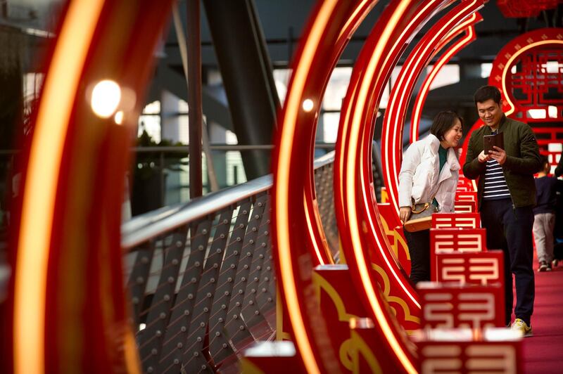 Visitors check their smartphones at a Lunar New Year display at an upscale shopping mall in Beijing. Mark Schiefelbein / AP Photo