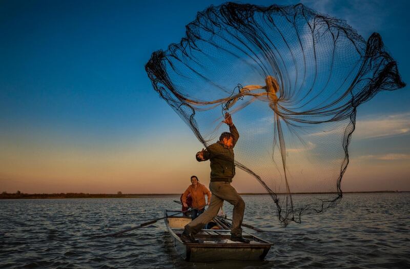 A fisherman throws a net while out on a boat with his wife in Yanhu village near Yangzhou, Jiangsu, China. Aleksandar Plavevski / EPA