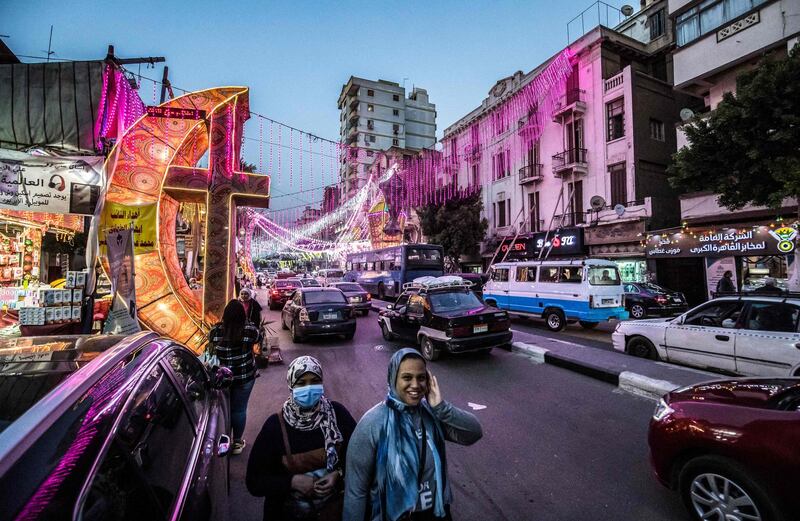 Pedestrians walk past a decoration depicting a giant crescent and cross - and a lantern across the street - erected to celebrate the start of the Muslim fasting month of Ramadan. AFP