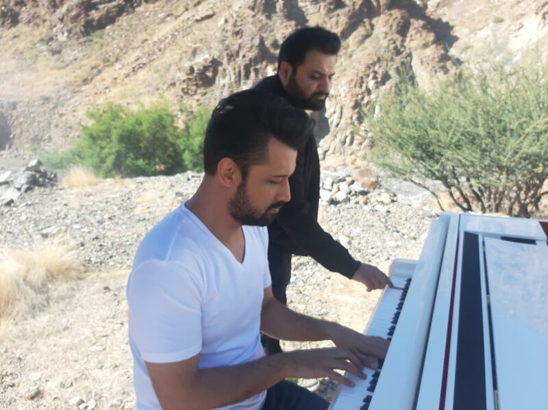 Two men playing a piano outdoors