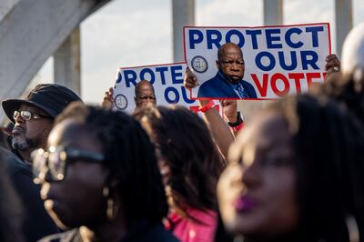 People march across the Edmund Pettus Bridge with placards bearing the image of the late John Lewis, for whom the most recent voting rights act is named. Getty Images / AFP
