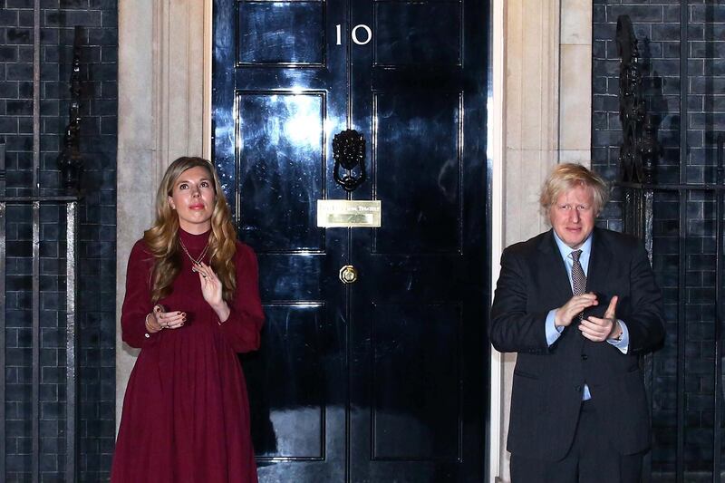 LONDON, ENGLAND - FEBRUARY 03: United Kingdom prime minister Boris Johnson and his fiancee Carrie Symonds take part in a doorstep clap in memory of Captain Sir Tom Moore outside 10 Downing Street on February 03, 2021 in London, England. WWII veteran, Sir Tom had raised nearly Â£33 million for NHS charities ahead of his 100th birthday last year by walking laps of his garden in Marston Moretaine, Bedfordshire. He was admitted to Bedford Hospital this weekend after testing positive for covid-19 and died on 2nd February with his family present. (Photo by Hollie Adams/Getty Images)