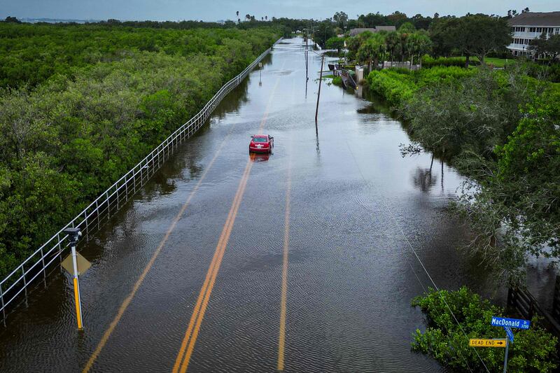 A car attempts to travel on a flooded road in Tampa, Florida. AFP