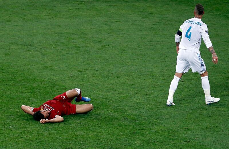 Real Madrid's Sergio Ramos walks away as Salah writhes in pain. Darko Vojinovic / AP Photo