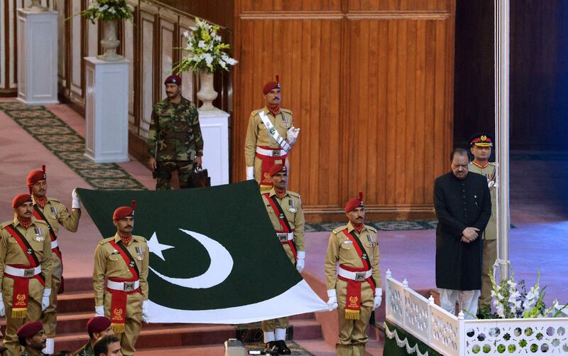 Pakistani soldiers carry the national flag prior to be hoisted by president Mamnoon Hussain, right, during a ceremony to mark the country's Independence Day in Islamabad. Aamir Qureshi / AFP Photo