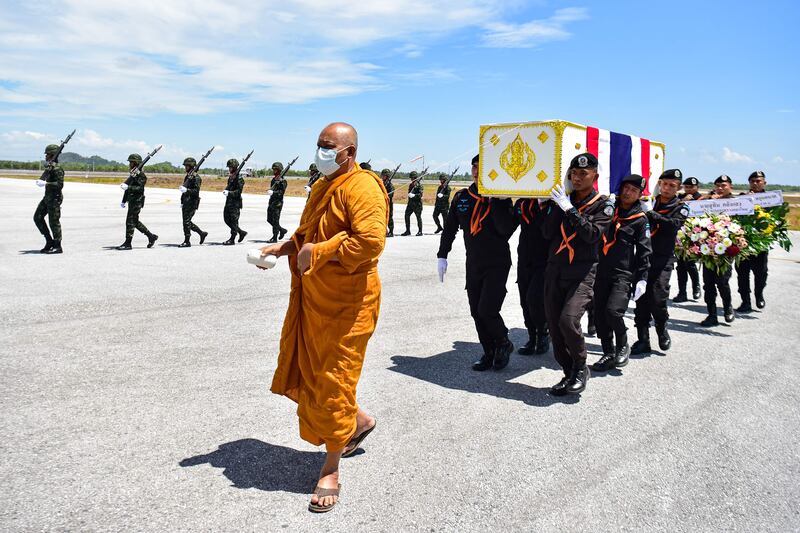 A monk walks with Thai soldiers carrying the coffins of two army rangers killed in an attack, during a ceremony at Narathiwat Airport in southern Thailand. AFP