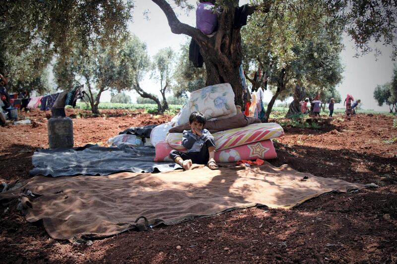 Esara'a son, Ahmad nine years old standing between the trees in Harm's mountain waiting for the tent to be set up, surrounded by blankets and a dove to sleep on.