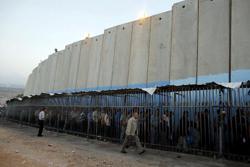 Palestinians wait to cross into Jerusalem next to Israel's barrier at a checkpoint near Bethlehem. Ammar Awad / Reuters
