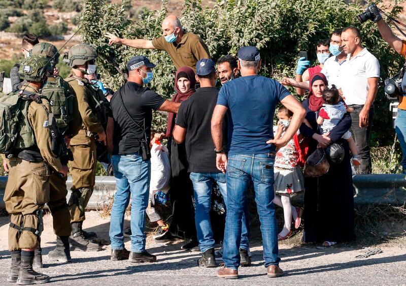 Palestinians are blocked by Israeli policemen and army soldiers, some clad in masks due to the Covid-19 pandemic, while on their way home at the entrance of a junction by the Palestinian village of Halhul, north of Hebron in the occupied West Bank, as Israeli settlers arrive to attend a rally against US President Donald Trump's peace plan. AFP