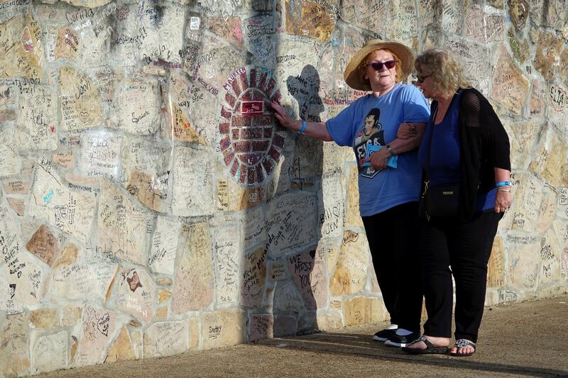 Cheryl Penny assists Ann Lawlor, left, who traveled from England to participate in the candle light vigil where mourners will gather to commemorate the 40th anniversary of the death of singer Elvis Presley at his former home of Graceland, in Memphis. Karen Pulfer Focht / Reuters