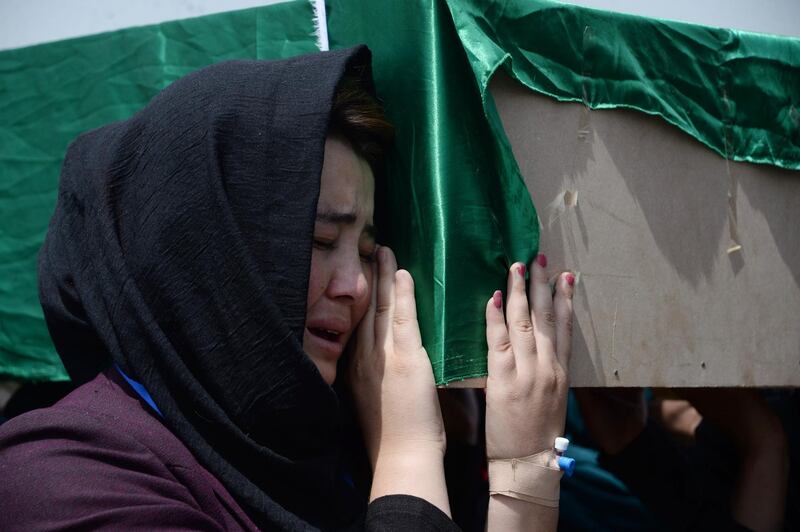An Afghan Shiite girl carries the coffin of a victim who were killed in a suicide attack the previous day, in Kabul on August 16, 2018. - Gunmen launched an attack on an intelligence training centre in Kabul on August 16, officials said, just a day after a suicide bomber killed dozens of students in the war-weary Afghan capital. (Photo by NOORULLAH SHIRZADA / AFP)