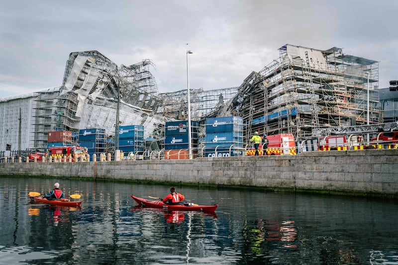 Tourists kayak on a canal alongside the historic former stock exchange Boersen after it went on fire and its outer wall collapsed in Copenhagen. AFP