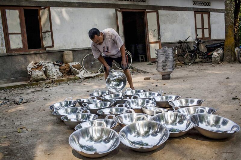 A worker collects pans that has been dried after polishing process at Putra Logam workshop in Yogyakarta, Indonesia. Ulet Ifansasti / Getty Images