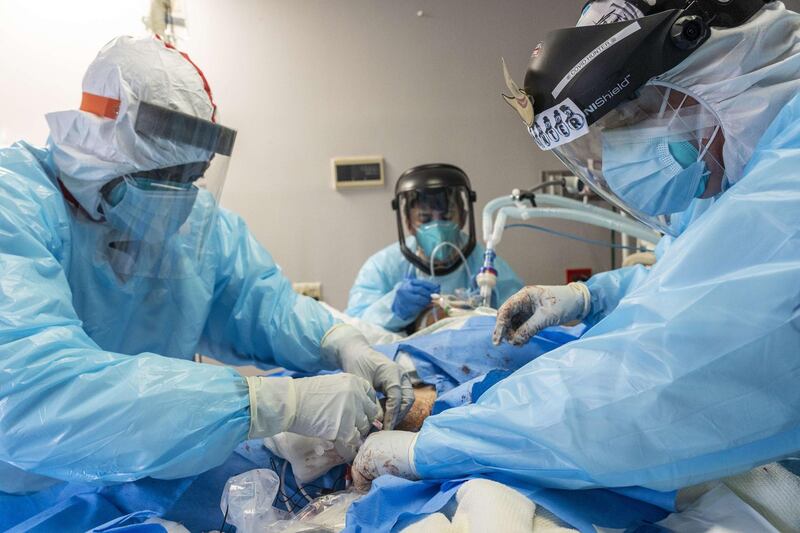 Dr Joseph Varon, right, and Jeffrey Ndove, left, perform a procedure for hypothermia treatment on a patient in the Covid-19 intensive care unit at the United Memorial Medical Centre in Houston, Texas. AFP