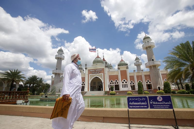 A Muslim man, wearing a face mask, holds a prayer mat at the Pattani Central Mosque in Pattani.  AFP