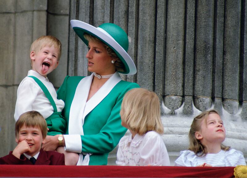A young Prince Harry sticking his tongue out, much to the surprise of his mother, Princess Diana, on the balcony of Buckingham Palace in 1988