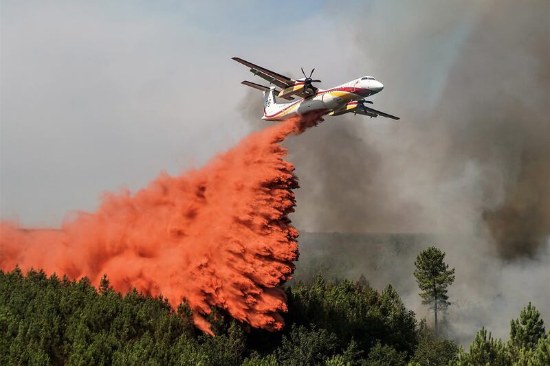 A plane douses a burning forest with fire retardant in Saint Magne. EPA