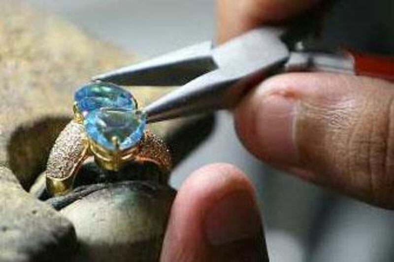 Worker fitting stones on different jewelry item in the mass production area of Damas factory in Dubai Multi Commodities Center.