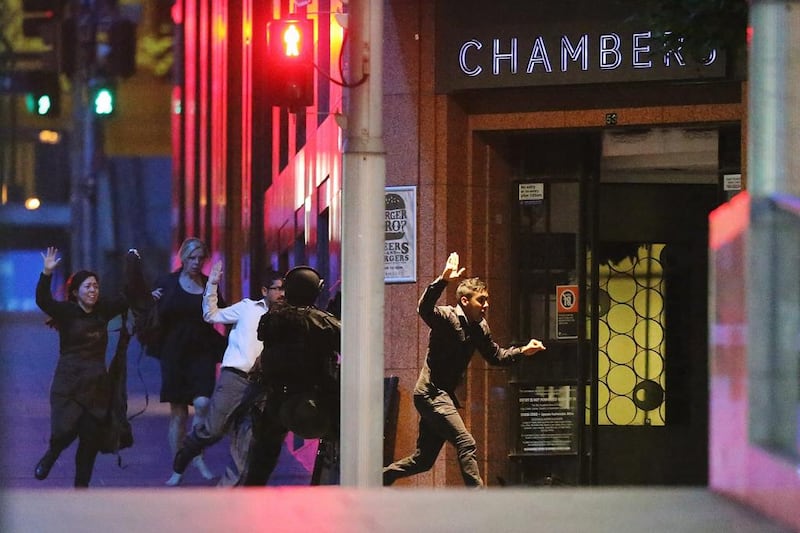 People run with there hands in the air as police storm the Sydney cafe where a gunman had been holding them hostage. Joosep Martinson/Getty Images