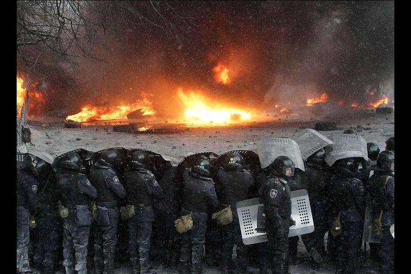 Interior Ministry members stand in formation in front of burning tyres set ablaze by pro-European protesters during clashes in Kiev January 22, 2014. Ukraine opposition leaders said on Wednesday there had been no concrete results from their talks with President Viktor Yanukovich to end weeks of street unrest and they called on protesters to prepare for a police offensive against them. REUTERS/Stringer (UKRAINE - Tags: POLITICS CIVIL UNREST)