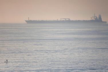 A man paddles on a surfboard near the Iranian oil tanker Grace 1 as it sits anchored after Gibraltar lifted the detention order. Reuters