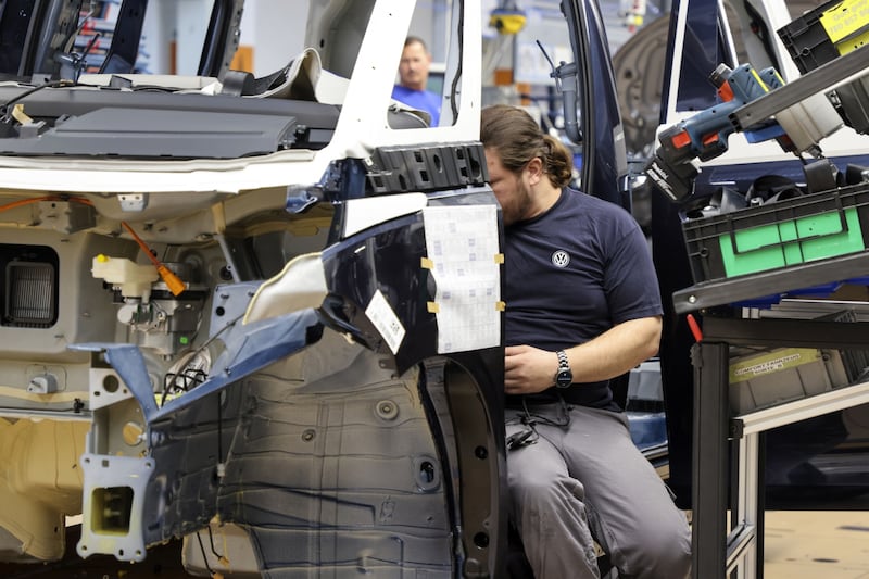 An employee fits components to the body of a Volkswagen ID Buzz electric microbus on the assembly line. Many car makers list climate change as business risk factors. Bloomberg