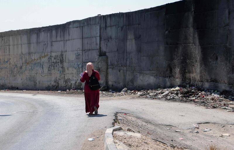 Palestinian student at Al-Quds University Aya Abu al-Amal, 18, makes her way to class along the wall separating East Jerusalem from the Palestinian village of Abu Dis, after an interview with AFP in the occupied West Bank village, on September 23, 2020. Two decades on from the Second Intifada, Palestinians who have grown up in the shadow of the uprising find themselves surrounded by barriers with little hope for the future. / AFP / Emmanuel DUNAND
