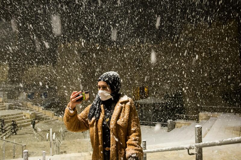A woman takes a photo in the snow at Damascus Gate in Jerusalem's old city on February 17, 2021 in Jerusalem, Israel, as wintery weather hits the country. Getty Images