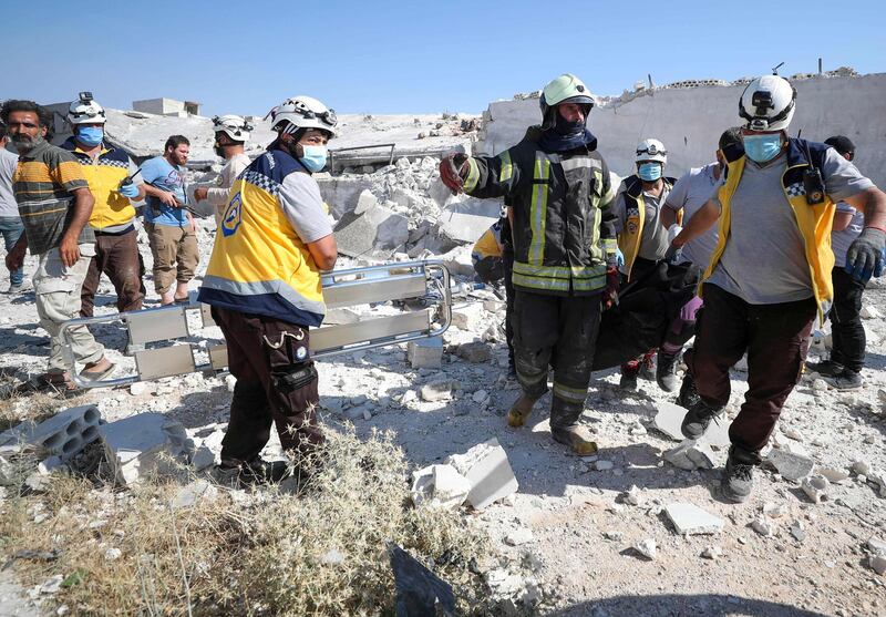 Syrian Civil Defence rescue workers, also known as White Helmets, carry a body away from the debris of a building following a reported explosion in Syria's northwestern city of Idlib.. AFP