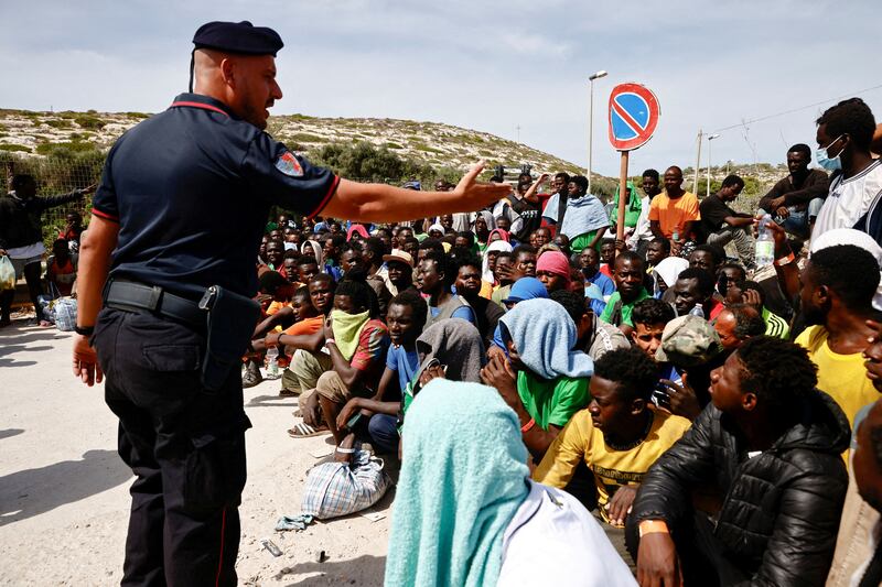 A member of the Carabinieri gestures towards migrants outside the hotspot, on the Sicilian island of Lampedusa, Italy, in September. Reuters