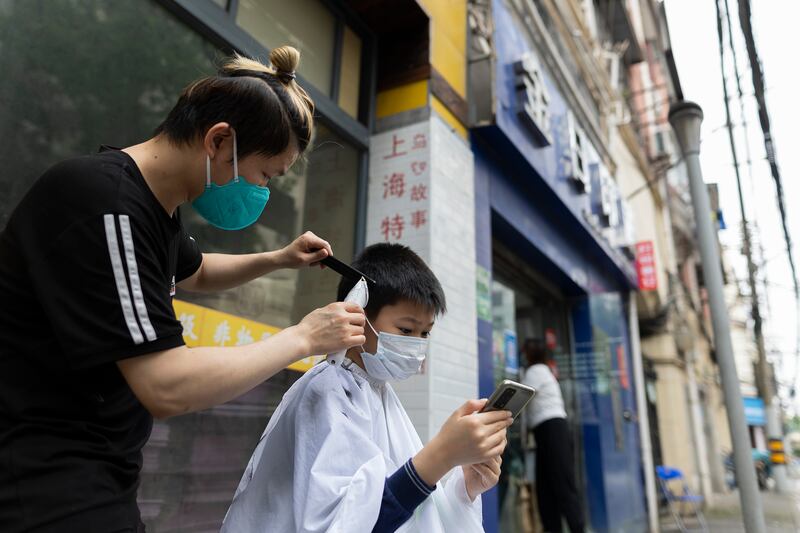 A barber cuts a boy's hair on a street. Getty Images