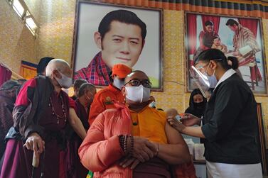 A health worker administers a dose of a Covid-19 coronavirus vaccine to a Buddhist monk sitting in front of a portrait of Bhutan's King Jigme Khesar Namgyel Wangchuck. AFP