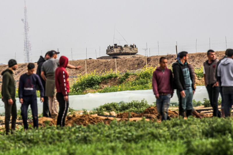 Palestinians demonstrate along along the Gaza-Israel border east of Khan Yunis in the southern Gaza Strip as an Israeli tank is seen across the other side. AFP