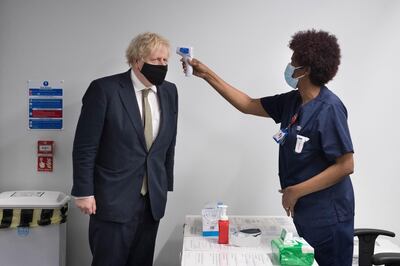 LONDON, ENGLAND - JANUARY 04 Prime Minister Boris Johnson has his temperature checked during a visit to view the vaccination programme at Chase Farm Hospital , part of the Royal Free London NHS Foundation Trust on the day that the NHS ramps up its vaccination programme with 530,000 doses of the newly approved Oxford/AstraZeneca Covid-19 vaccine jab available for rollout across the UK on January 4, 2021 in London, England. The Oxford-AstraZeneca covid-19 vaccine was administered at six hospitals today before being rolled out to hundreds of GP-led sites across the country this week.  (Photo by Stefan Rousseau - WPA Pool / Getty Images)