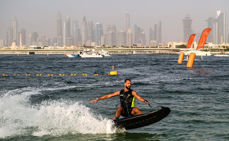 An athlete rides a jet-powered surfboard on the first day of the Dubai watersport festival, organised by the Dubai International Marine Club (DIMC), near the Burj Khalifa skyscraper in the Gulf emirate on June 25, 2020.  / AFP / KARIM SAHIB
