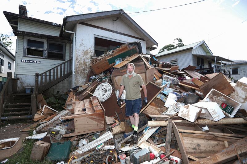 Resident Ken Bridge stands on a pile of his flood-damaged furniture outside his home in Lismore. AP