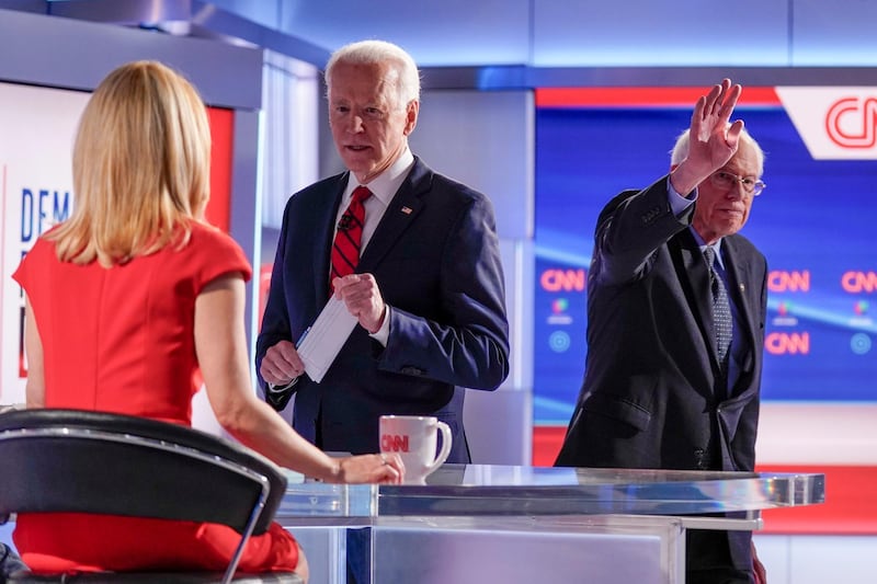 Former Vice President Joe Biden stops to talk with CNN anchor Dana Bash, left, as Senator Bernie Sanders waves after the debate. AP Photo