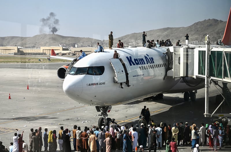 People clamber on top a plane at the Kabul airport on August 16, 2021. AFP