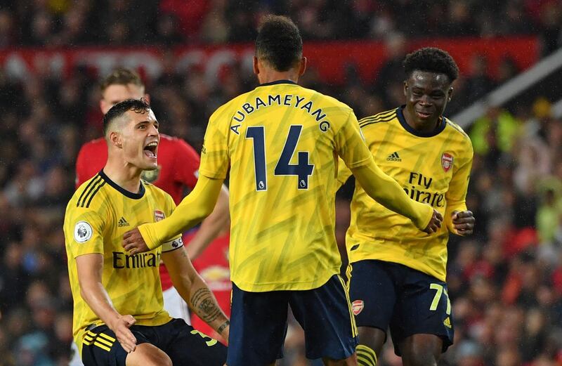 Arsenal's Gabonese striker Pierre-Emerick Aubameyang (C) celebrates with Arsenal's Swiss midfielder Granit Xhaka (L) and Arsenal's English striker Bukayo Saka (R) after scoring their first goal, decision of off-side overturned by VAR (Video Assistant referee) during the English Premier League football match between Manchester United and Arsenal at Old Trafford in Manchester, north west England, on September 30, 2019. RESTRICTED TO EDITORIAL USE. No use with unauthorized audio, video, data, fixture lists, club/league logos or 'live' services. Online in-match use limited to 120 images. An additional 40 images may be used in extra time. No video emulation. Social media in-match use limited to 120 images. An additional 40 images may be used in extra time. No use in betting publications, games or single club/league/player publications.
 / AFP / Paul ELLIS / RESTRICTED TO EDITORIAL USE. No use with unauthorized audio, video, data, fixture lists, club/league logos or 'live' services. Online in-match use limited to 120 images. An additional 40 images may be used in extra time. No video emulation. Social media in-match use limited to 120 images. An additional 40 images may be used in extra time. No use in betting publications, games or single club/league/player publications.
