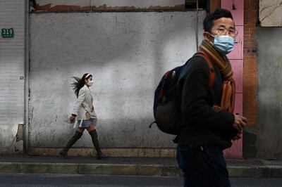 Poeple wearing protective face masks walk along a street in Shanghai on February 17, 2020. The death toll from China's new coronavirus epidemic jumped to 1,770 after 105 more people died, the National Health Commission said February 17. / AFP / Noel Celis
