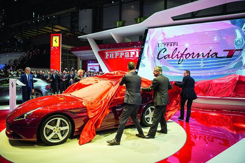 Ferrari president Luca Cordero di Montezemolo, left, looks on as men unveil the brand's latest car, the California T, at the Geneva Motor Show. AFP photo