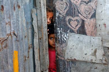 Palestinian children peep from behind a makeshift door at an empoverished neighbourhood in Gaza City on July 4, 2019. / AFP / MOHAMMED ABED