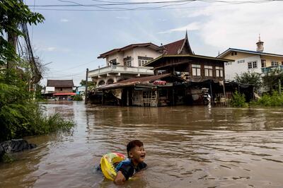A child swims in floodwaters after a tropical storm in Thailand. Scientists warn global warming will make extreme weather more common. AFP 