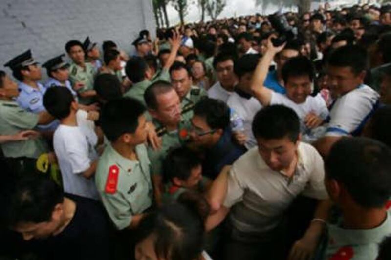 People fight for positions near a ticket booth at the Olympic Green on July 25 in Beijing, China.