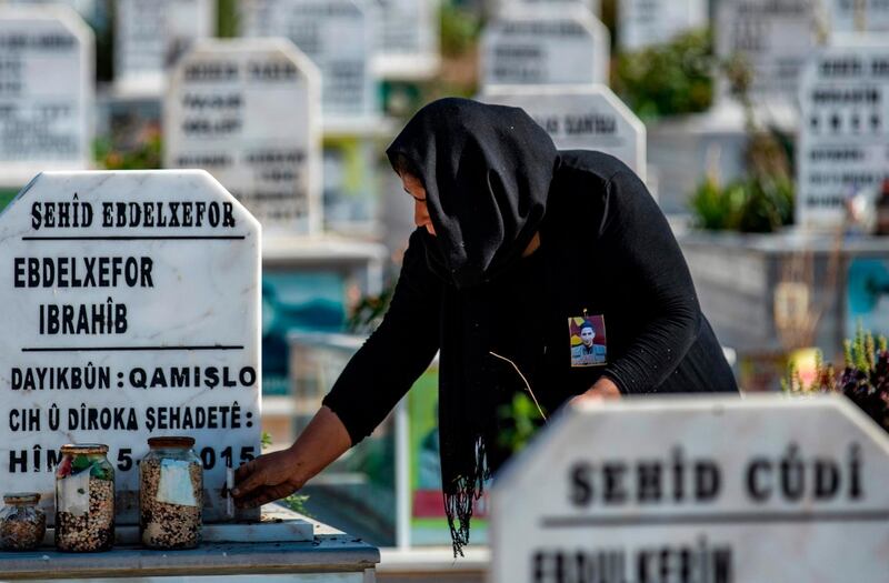 A Syrian Kurdish woman places a candle on a grave at a cemetary in Qamishli in the northeastern Hasakeh province on November 7, 2019, during a funeral for fighters from the Kurdish-majority Syrian Democtratic Forces (SDF) killed during clashes in Ras Al-Ain with Turkish and Ankara-backed forces.  / AFP / Delil SOULEIMAN
