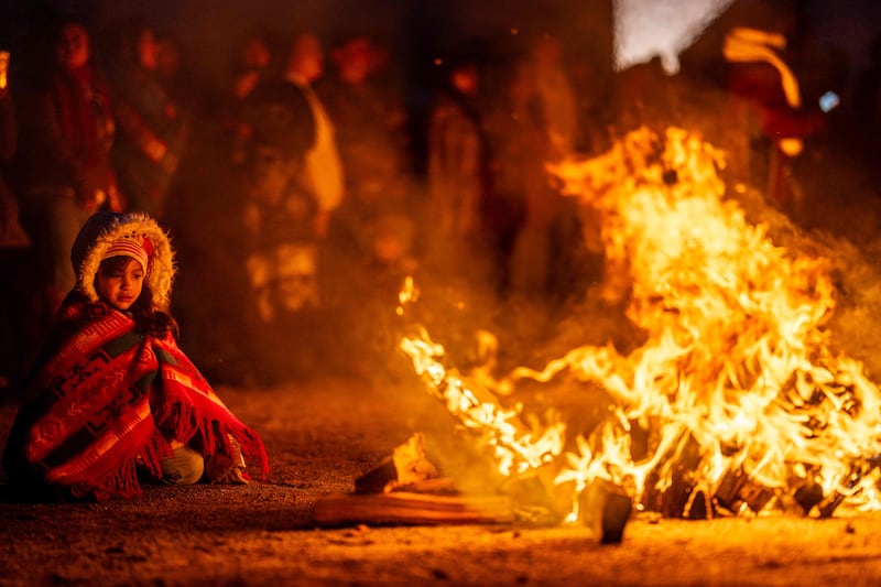 A child sits by a bonfire while members of the Ohkay Owingeh pueblo participate in the Matachinas dance in celebration of Christmas, San Juan Pueblo, New Mexico. AFP
