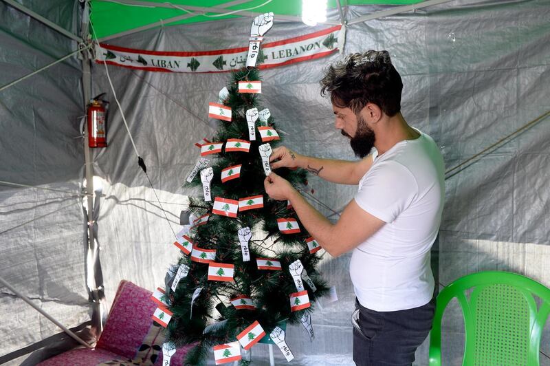 An anti-government protester decorates a Christmas tree with Lebanese flags and the 'revolution fist' inside his tent in Martyr Square, downtown Beirut, Lebanon.  EPA